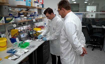 Prof Matt Trau standing in the lab with Dr Alain Wuethrich looking at the tiny chips